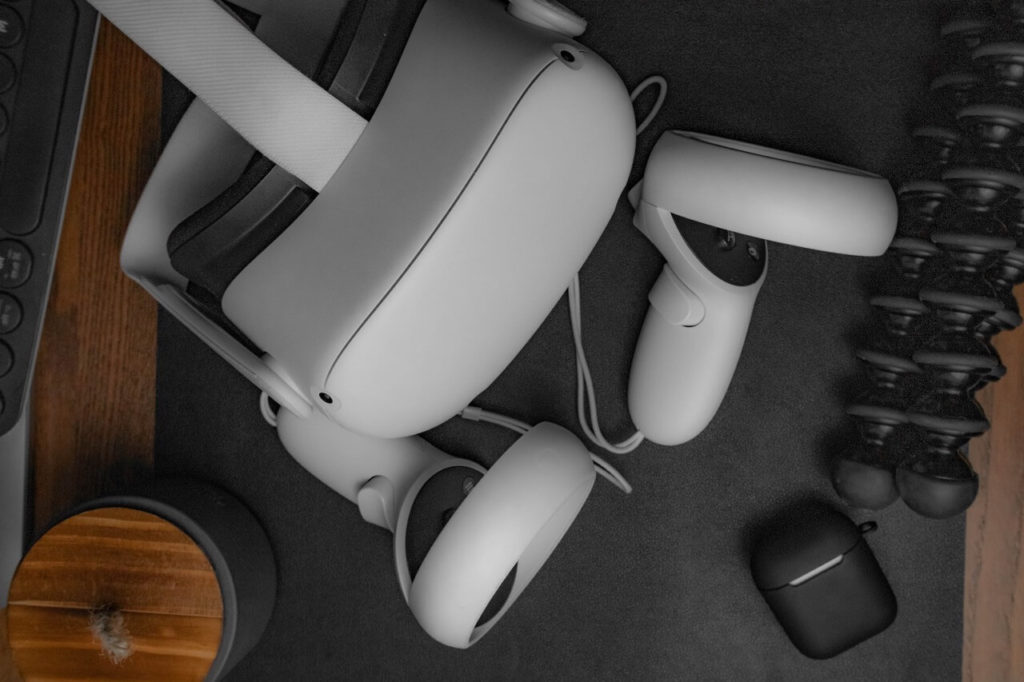 virtual reality goggles and connected handheld device sitting on desk with Apple iPods and other tech accessories.